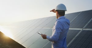 An-young-engineer-is-checking-with-tablet-an-operation-of-sun-and-cleanliness-on-field-of-photovoltaic-solar-panels-on-a-sunset