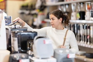 Young woman stands in a store near a counter with appliances